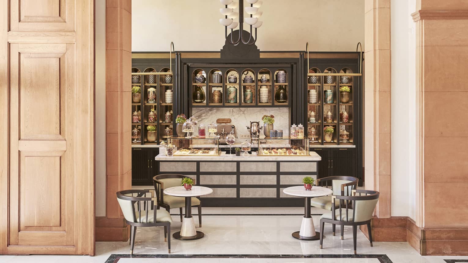 A pastry store with small tables and chairs and a counter with an assortment of pastries and treats.