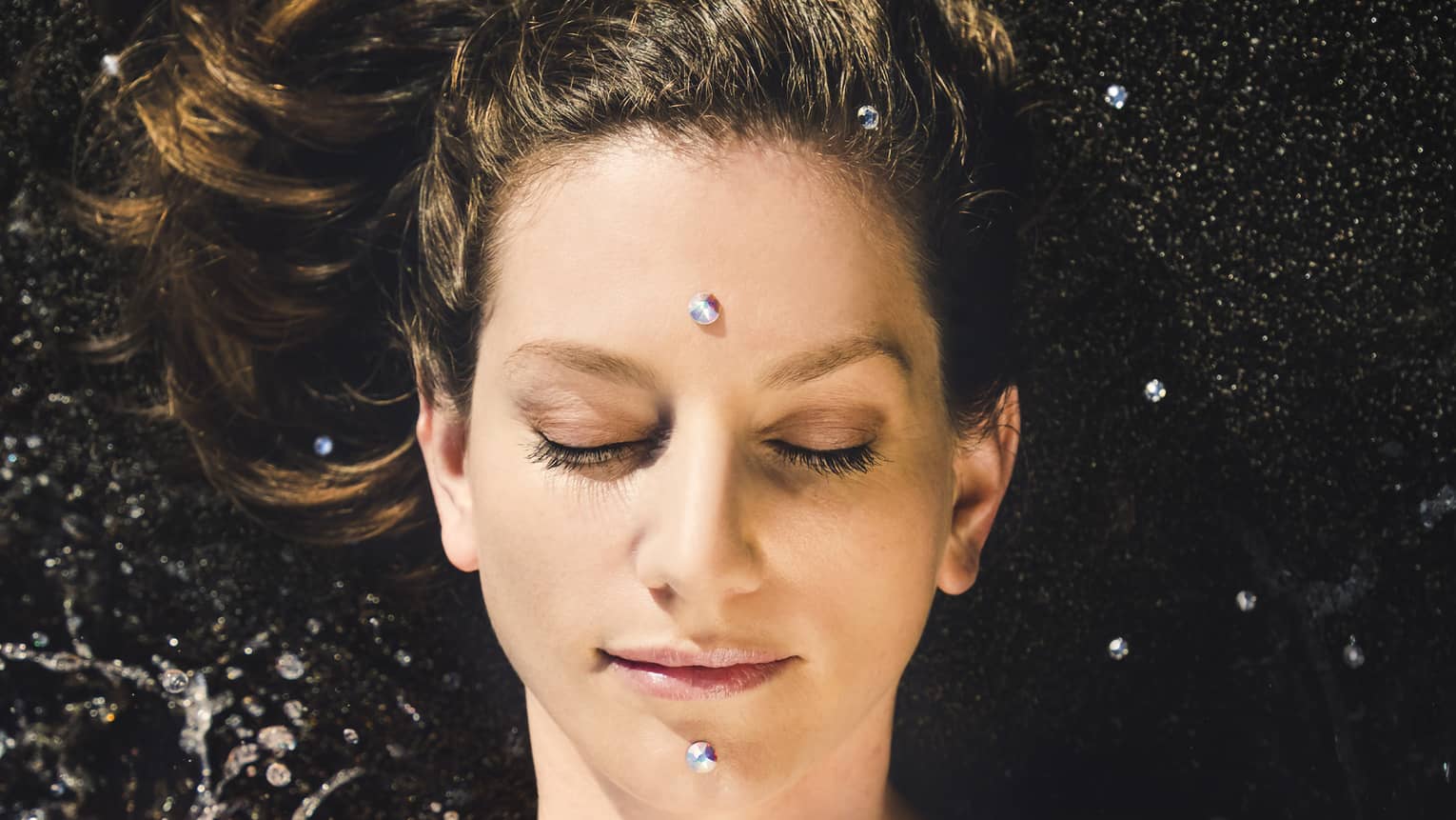 A woman enjoys a facial; two "black diamonds" are placed on forehead and chin