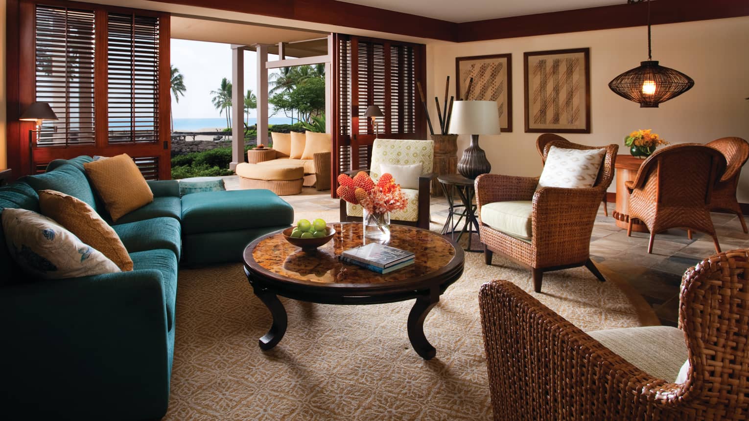 Deluxe Suite L-shaped blue sofa, round table, wicker chairs, open patio door