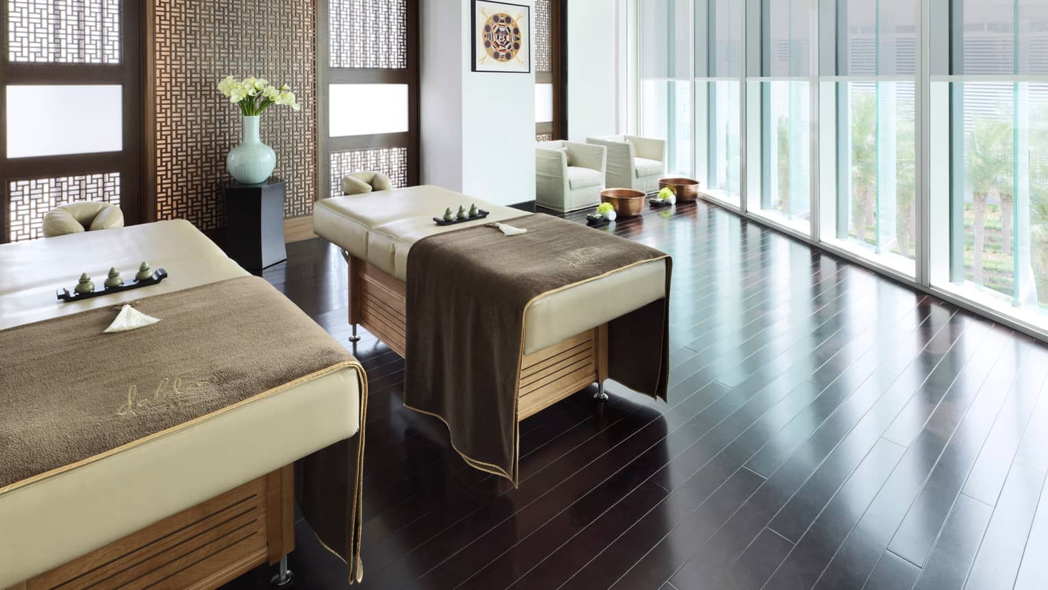 A couple's treatment room with floor-to-ceiling windows overlooking a garden. 