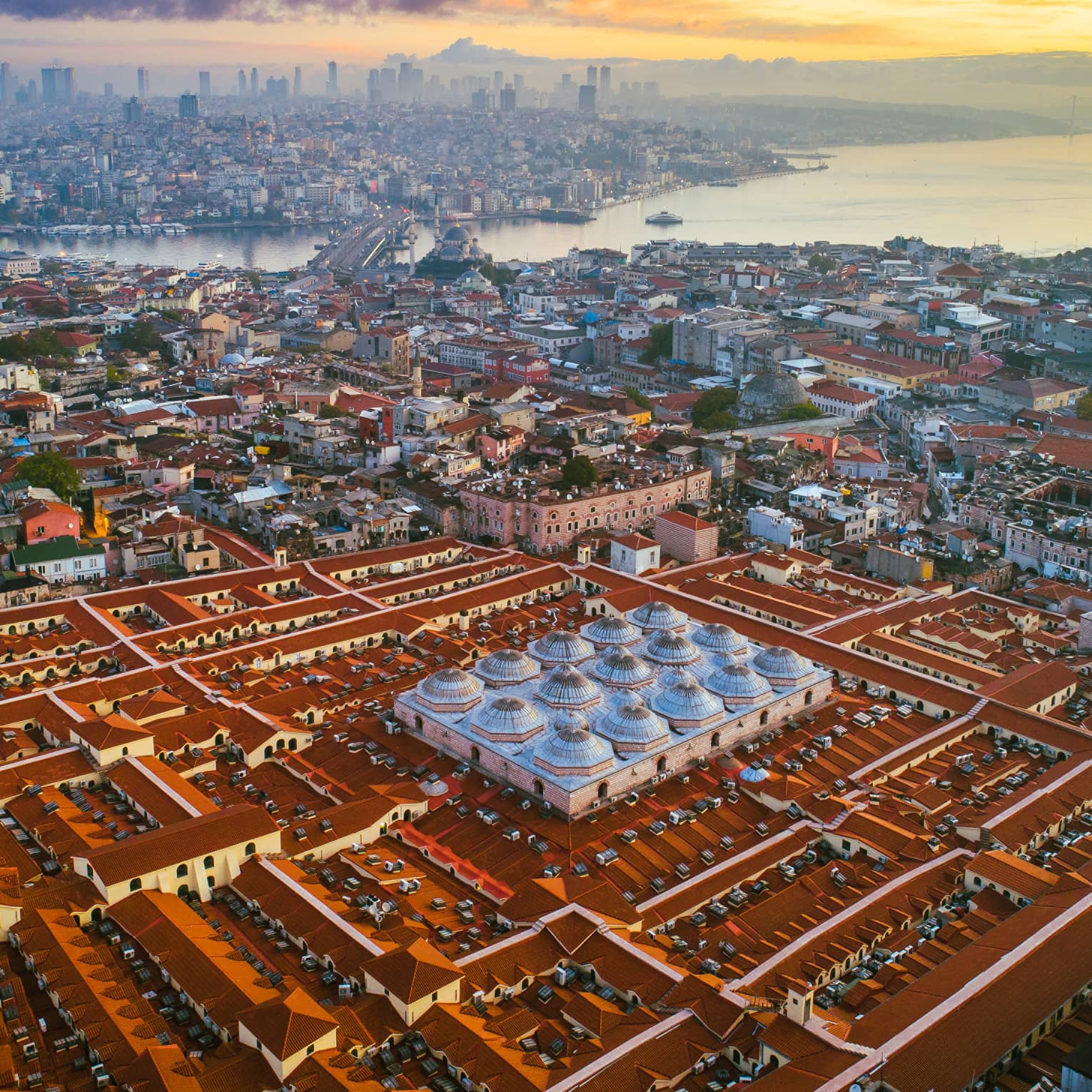 Aerial view of city rooftops, buildings and bridge at sunset