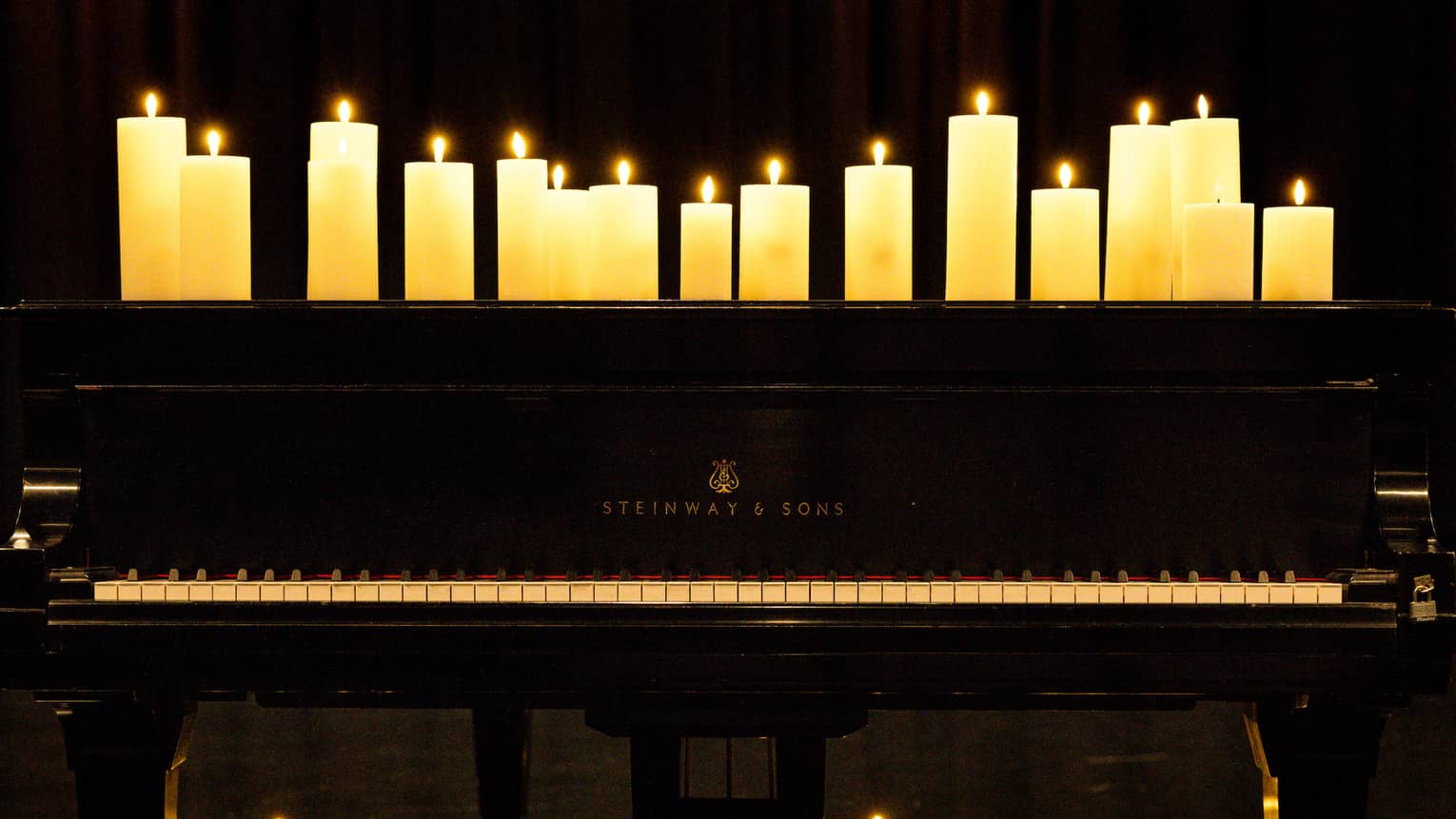 Pillar candles fill the top of a black piano