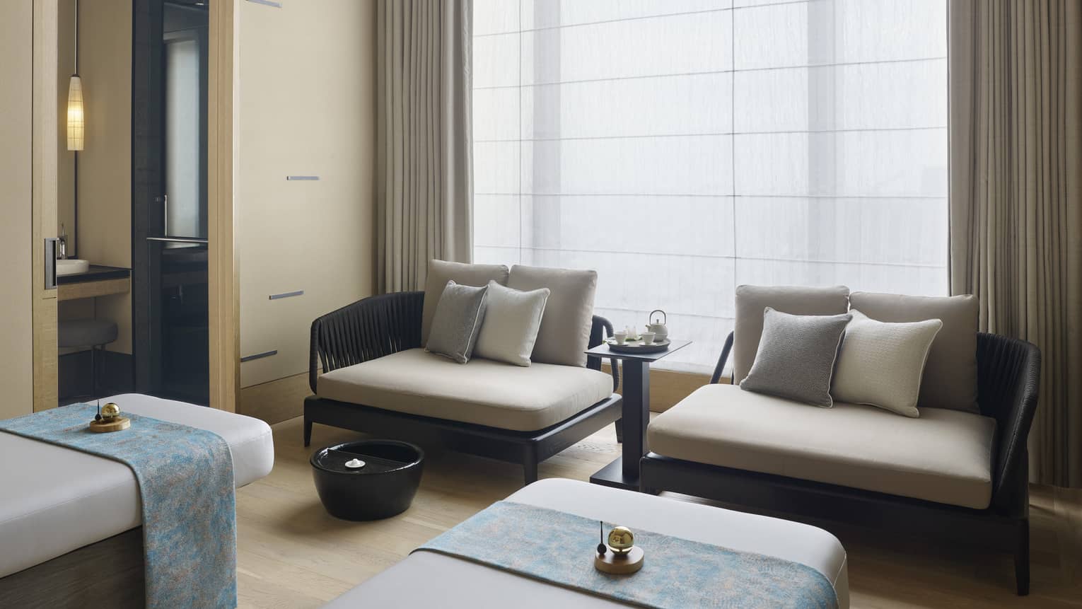 Couples Treatment Room, two spa treatment beds and small sofas under tall window