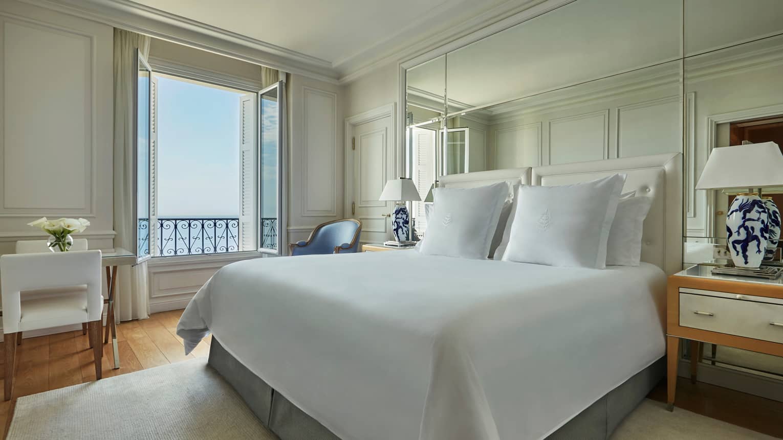 Hotel room, bed with white linens, dining table, open window