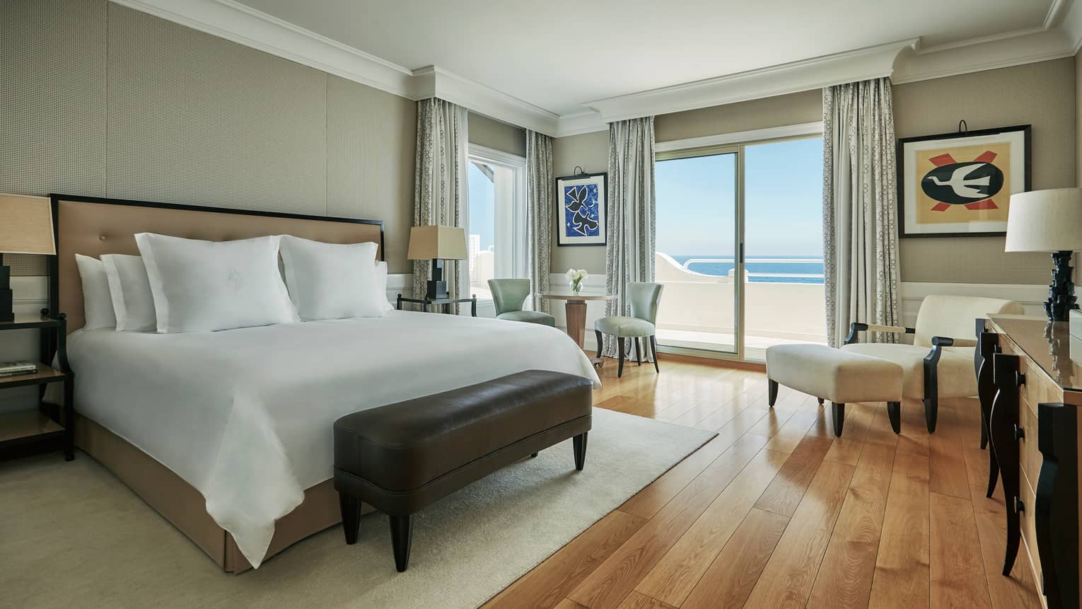 Palace Sea-View room with white bed, leather bench, dining table, armchair by balcony