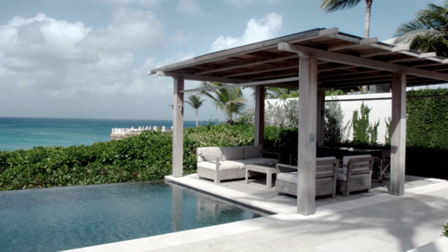 Patio cabana seating area over outdoor plunge pool, ocean in background