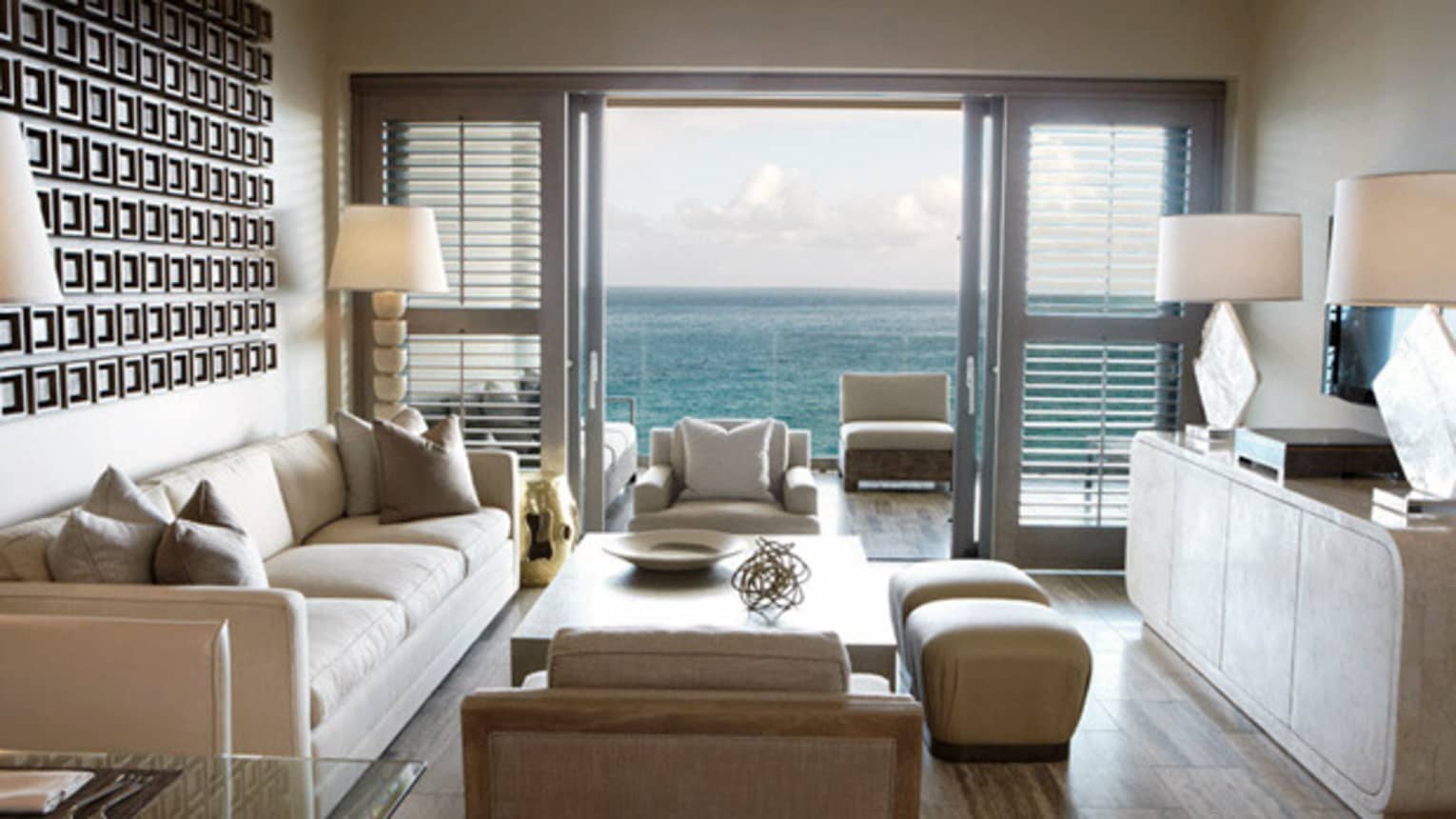 One-Bedroom Ocean-View Suite living room with white sofa and armchairs, patio door with ocean view