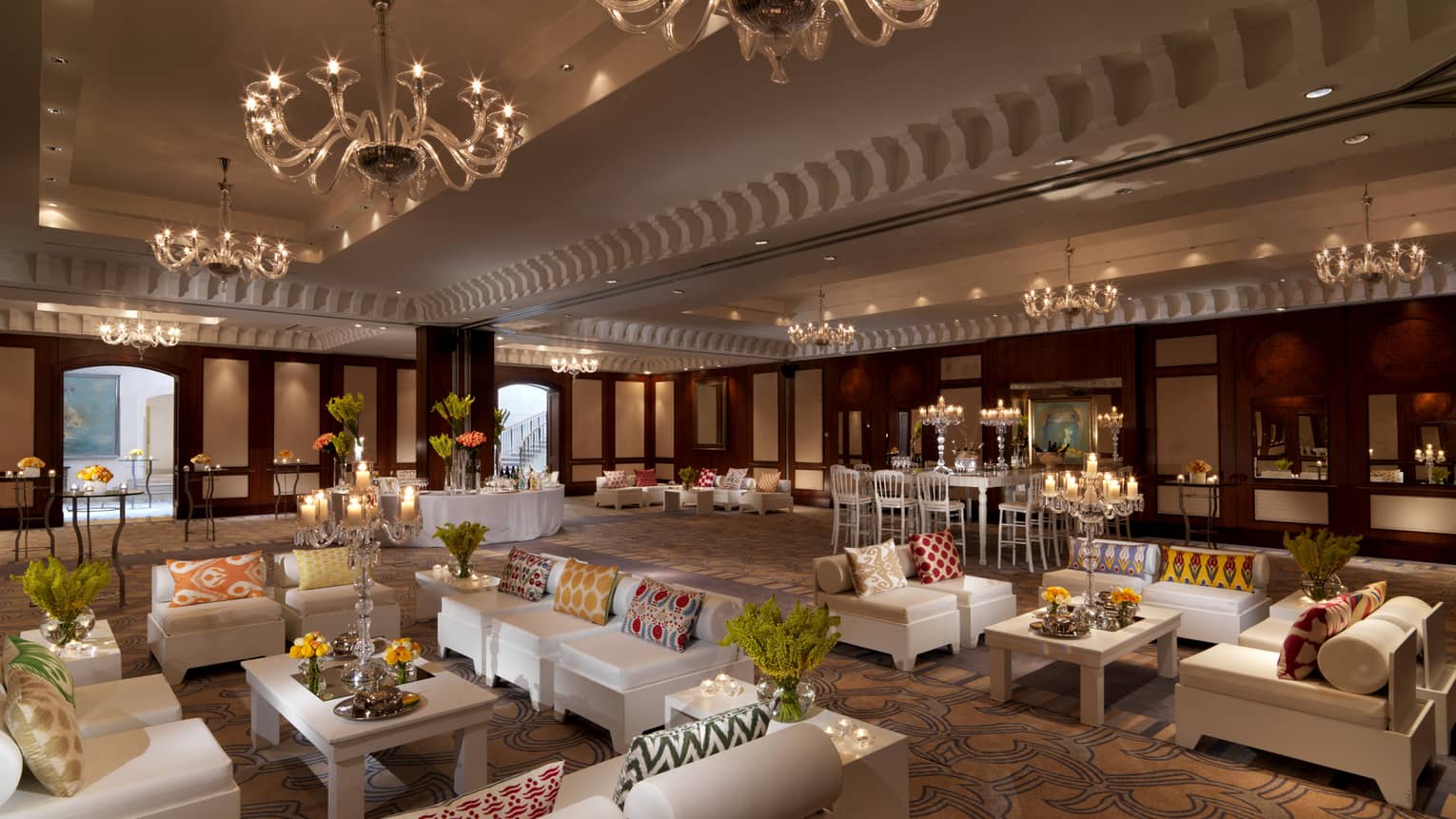 Ballroom with white sofas and chairs arranged in lounges under chandeliers