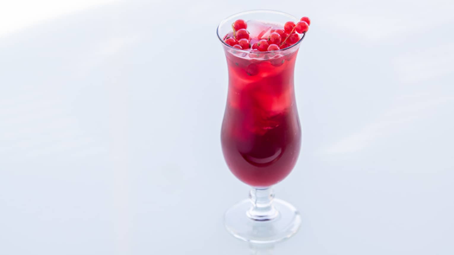 A burgundy coloured drink with hibiscus at the top.