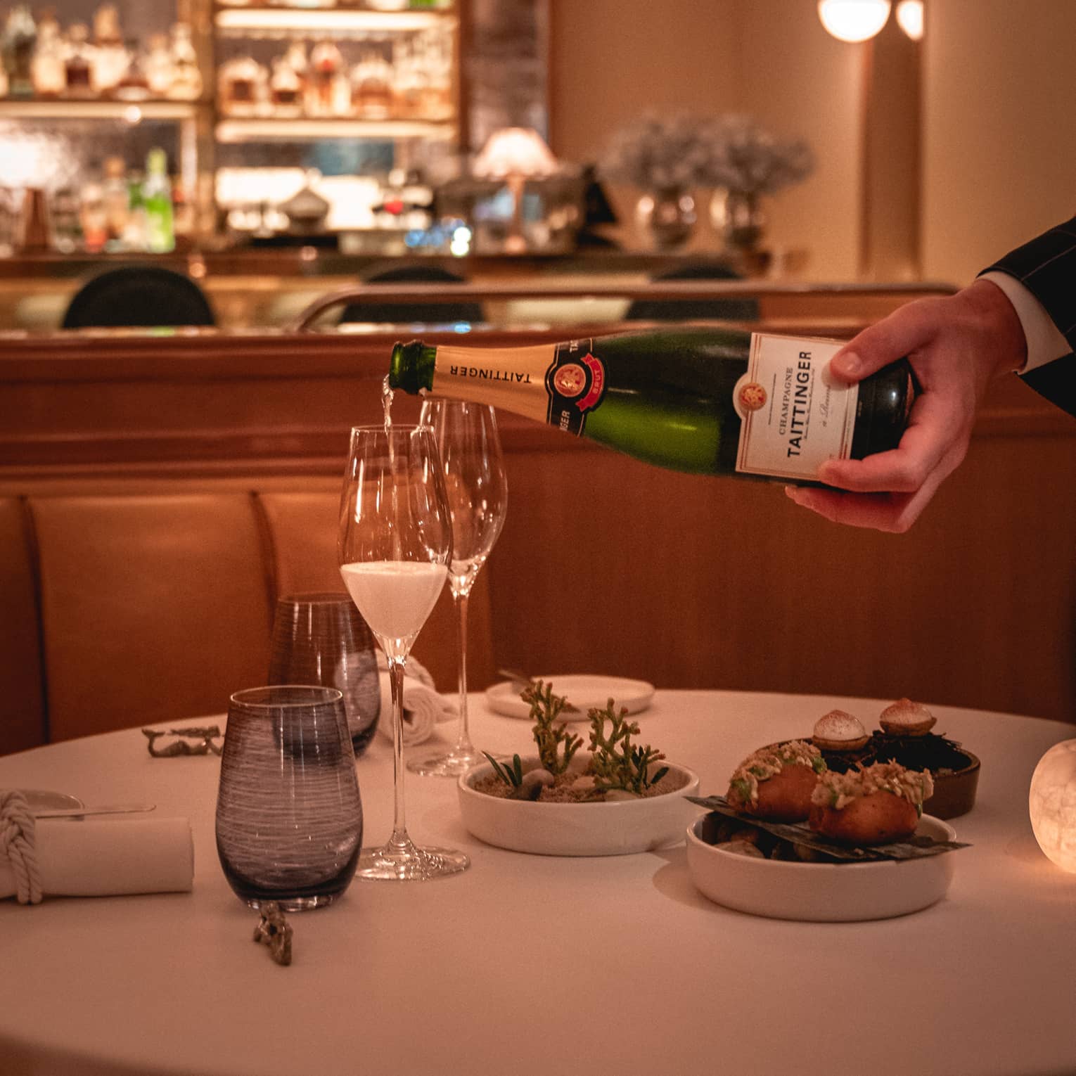 Server pours champagne into a glass on restaurant dining table