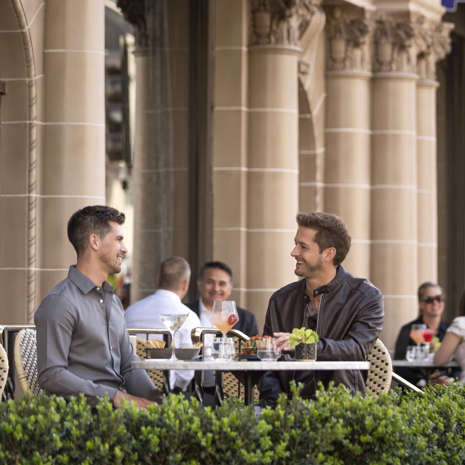 Two men eating at a patio outside.