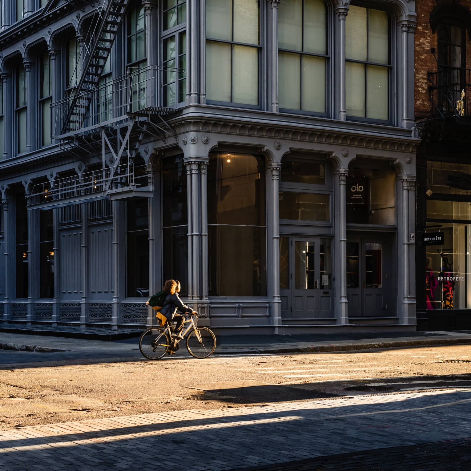Person rides bike on street past New York City SoHo building