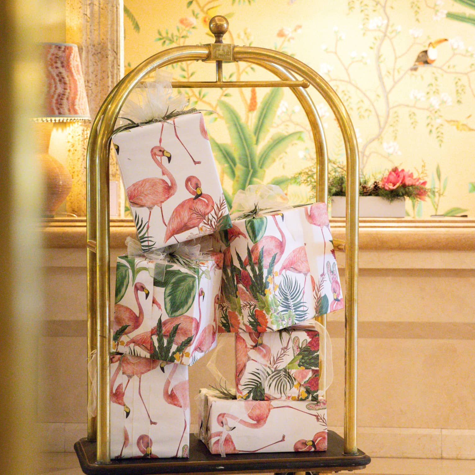 Luggage cart filled with presents wrapped in pink flamingo wrapping paper