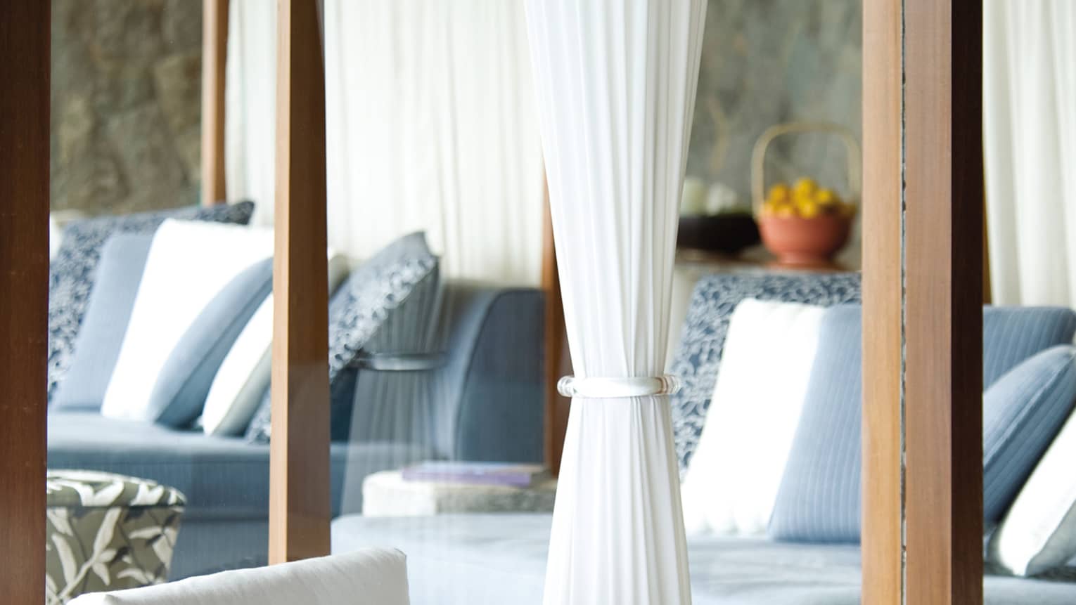 Close-up of white stone armchair with white cushion, tea pots on table