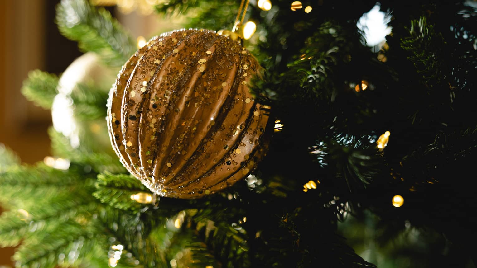 Gold ornament hangs on a Christmas tree