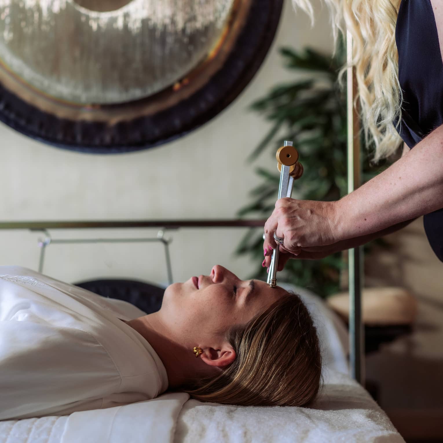 A woman receiving a sound healing treatment at a spa.