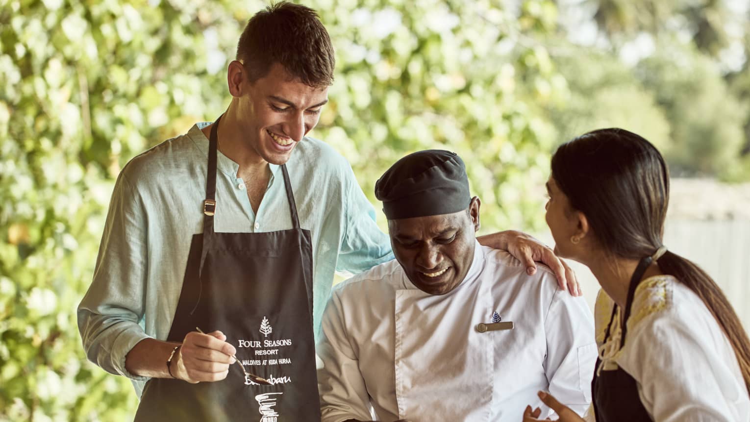 Chef teaches two guests how to make traditional Indian dish in outdoor kitchen