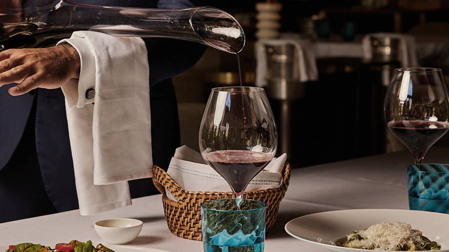Red wine being poured into a glass from a long-necked decanter