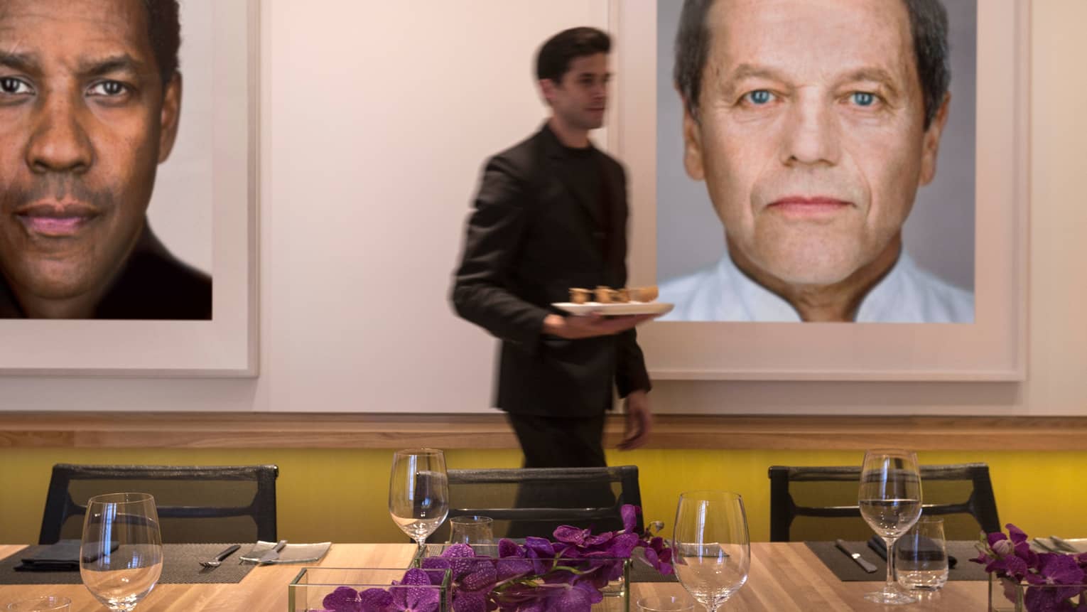 Server carries tray past Cut table, framed prints of Hollywood stars