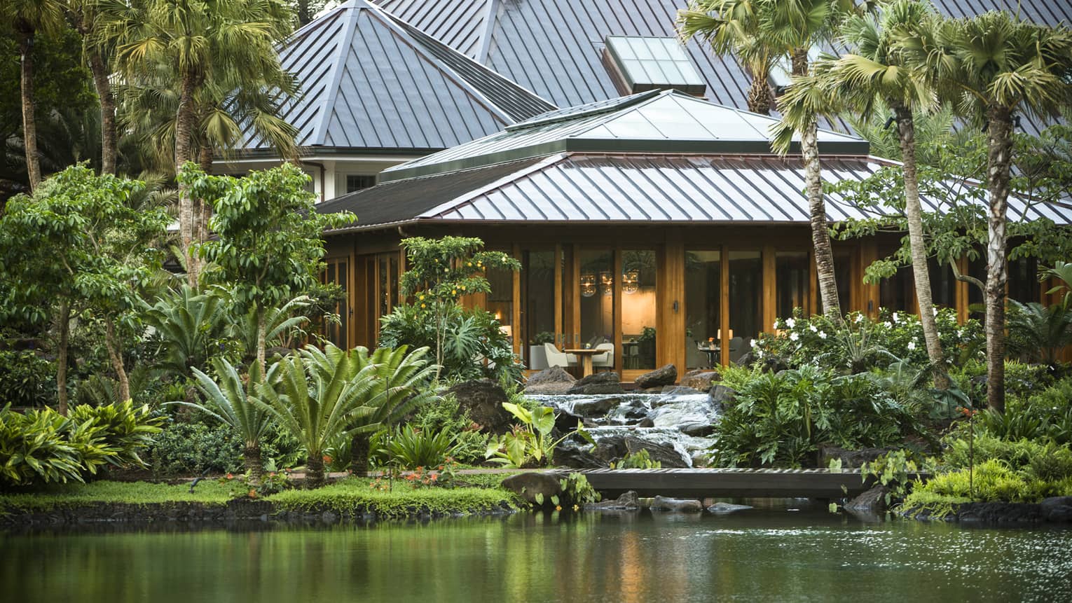 Exterior of Sensei, A Four Seasons Resort nestled in lush tropical foliage and located in front of a pond