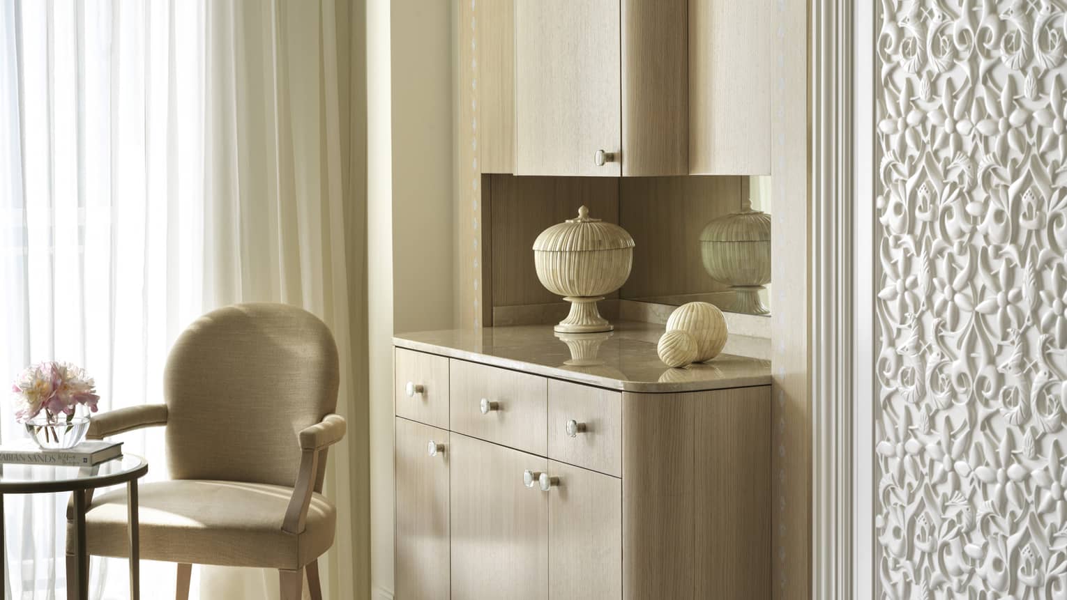 Detailed white walls of a hotel room entryway, with a chair and side table