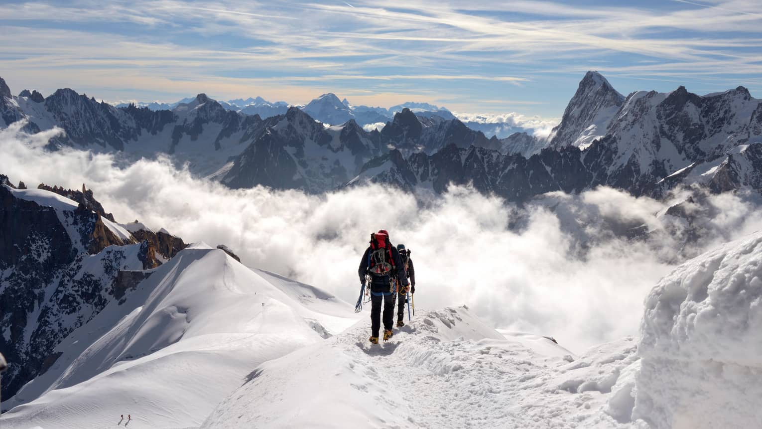 Two people hiking at top of icy mountain in French Alps