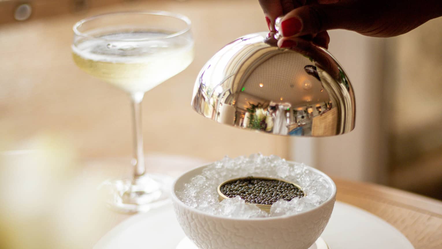 Caviar on ice next to a glass of wine.