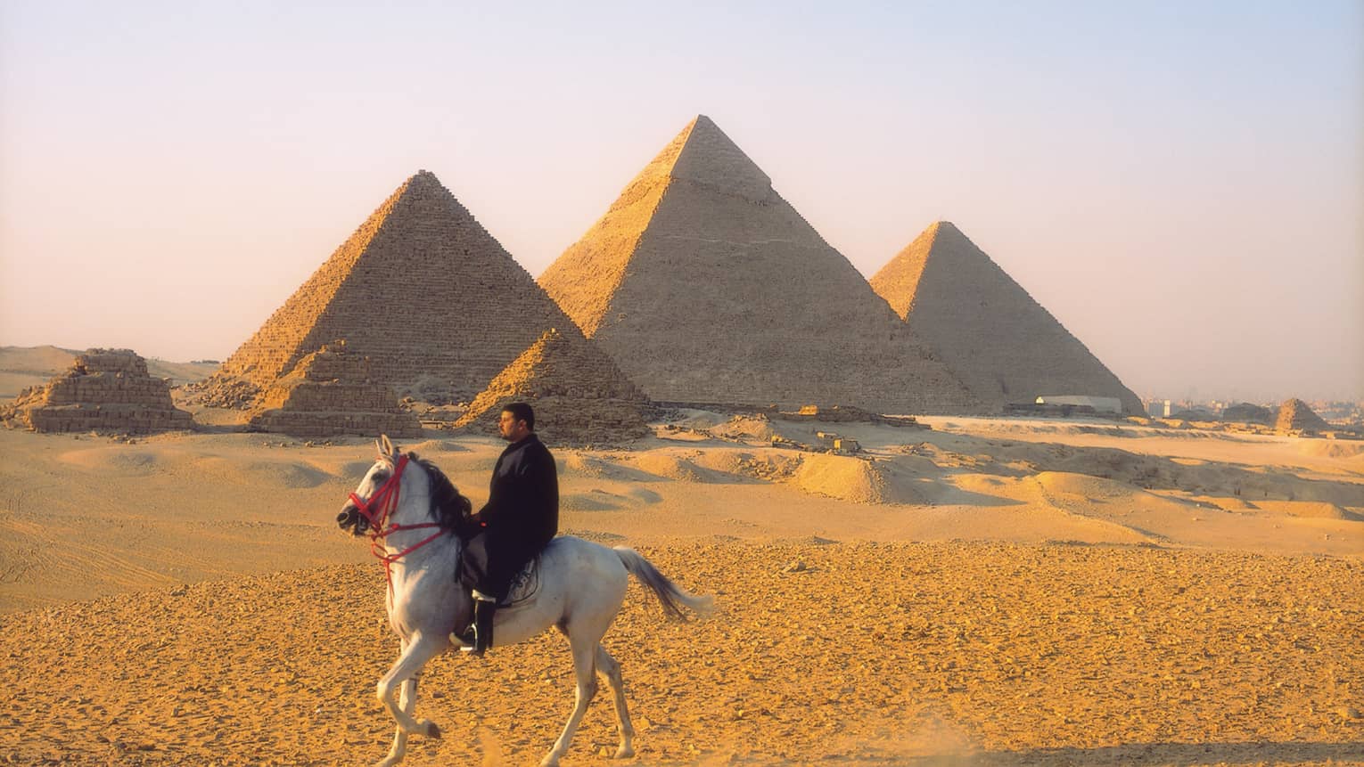 Horseman riding by pyramids