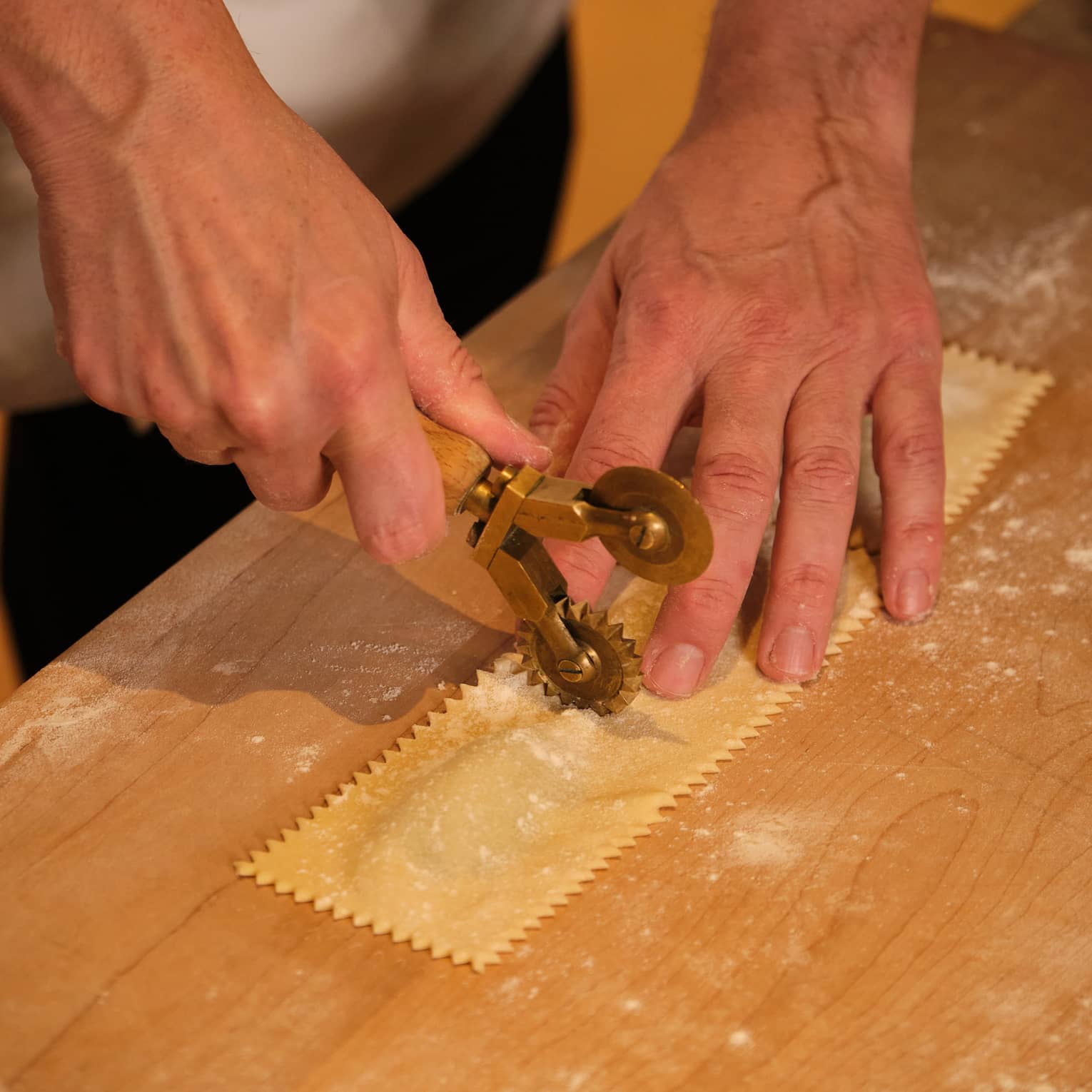 A chef crimping a sheet of ravioli pasta