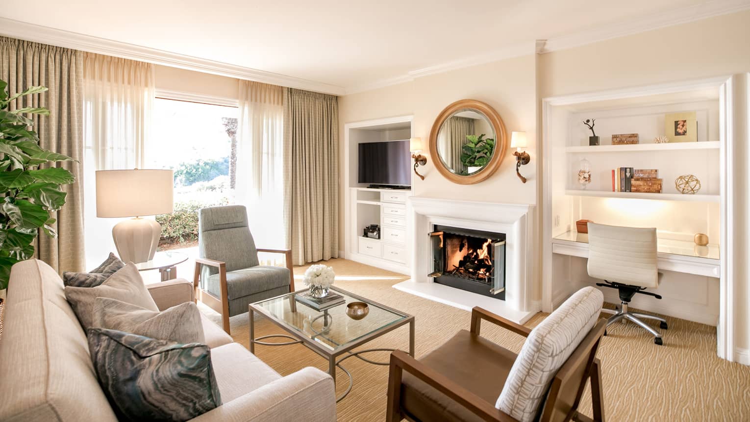 Sunny, modern villa seating room with white fireplace under round mirror, by built-in desk