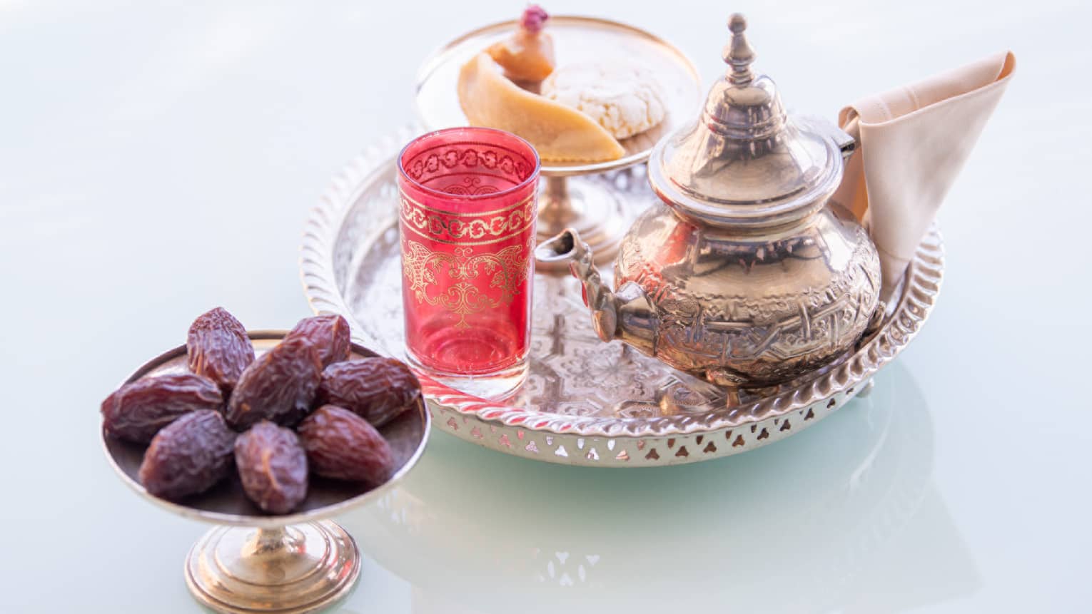 A silver platter of tea served with a plate of dates.