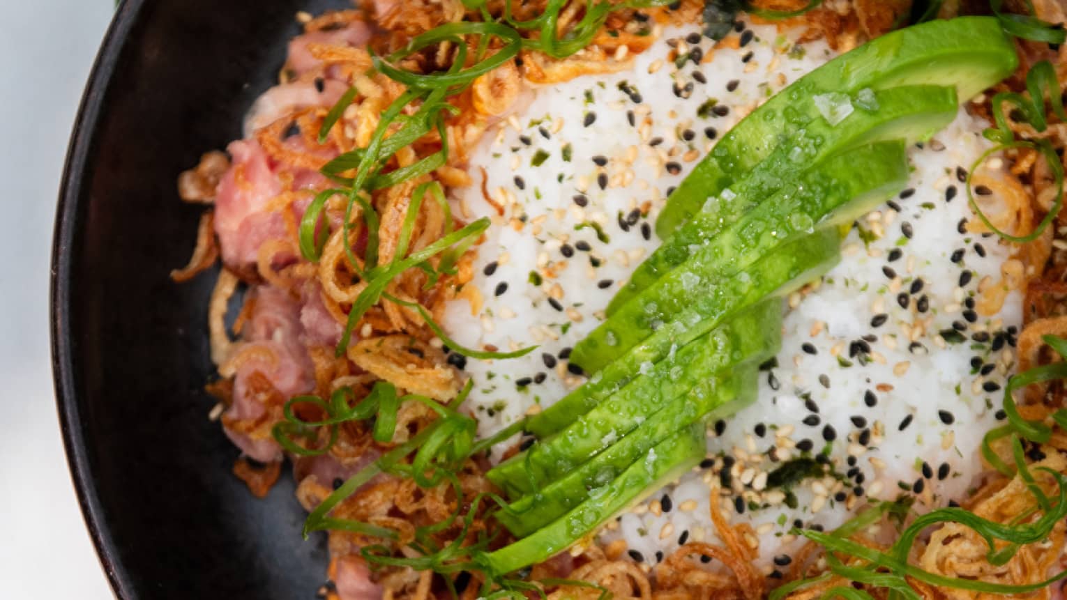 Spicy tuna poke bowl in a round black dish