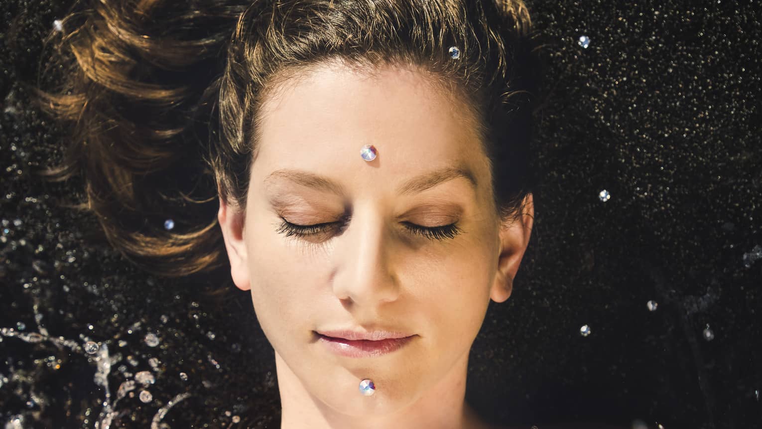 A woman enjoys a facial; two "black diamonds" are placed on forehead and chin