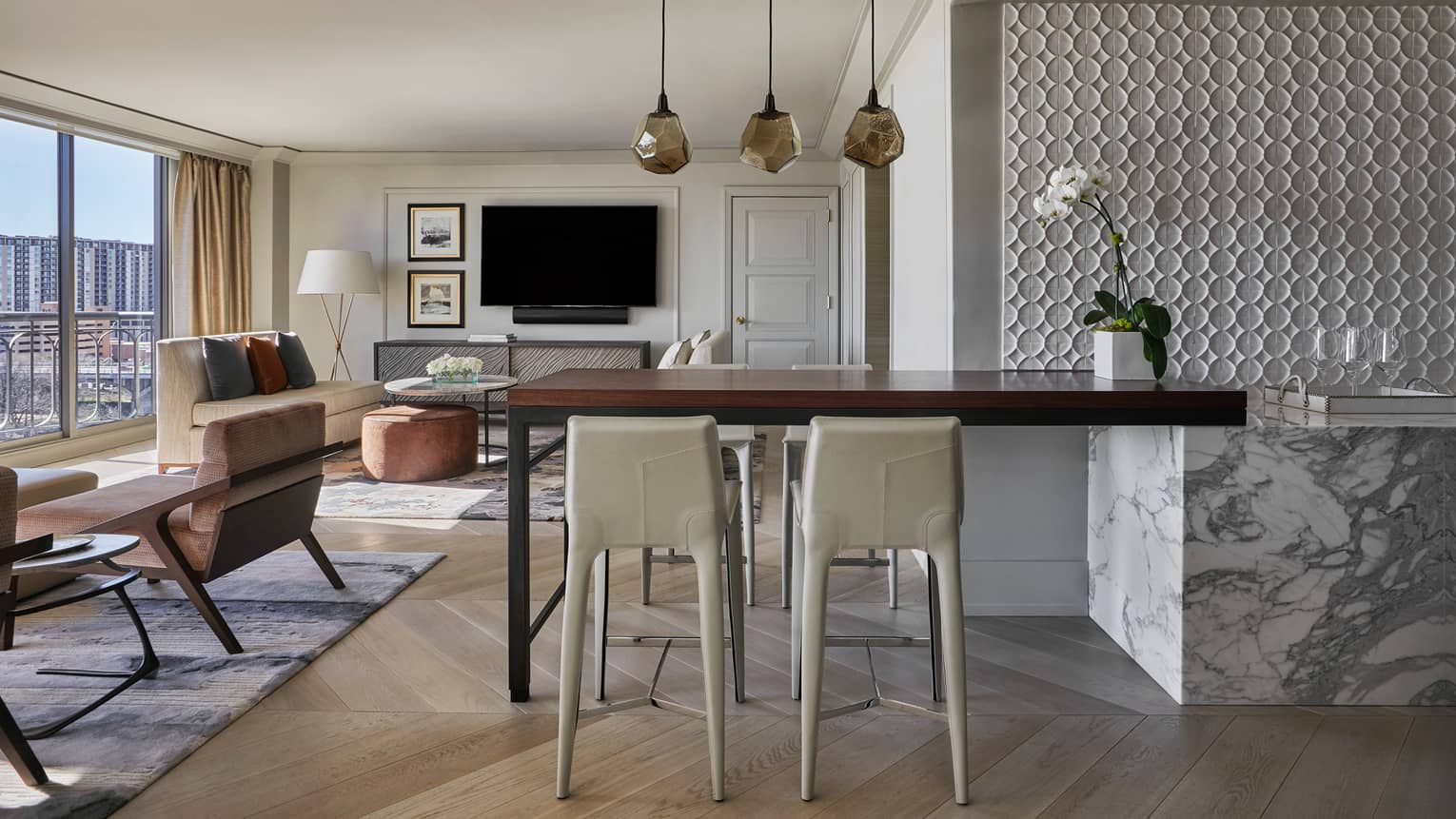 Governor's Suite white stools at tall wood table, three modern hanging lights, bright living room