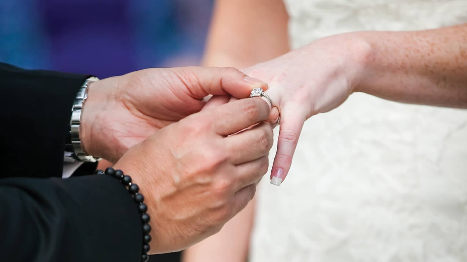 Groom placing wedding ring on bride's finger