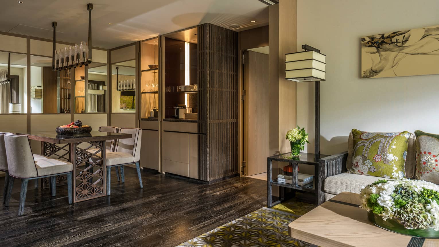 Stylish living and dining area with a modern dining table, a comfortable sofa with green accent pillows and warm lighting at Four Seasons 