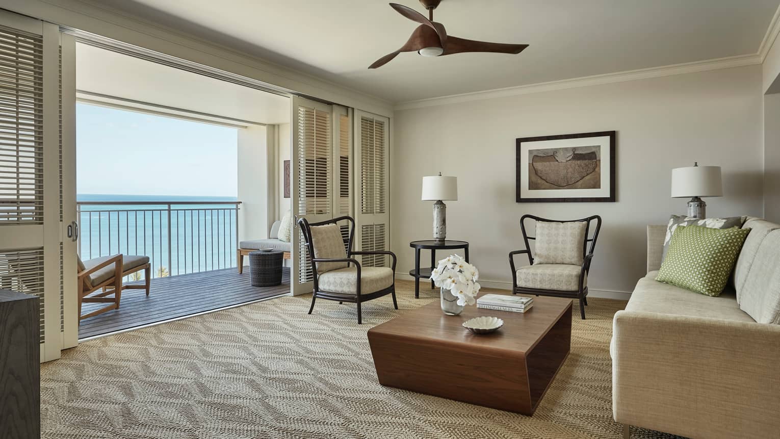 Oceanfront Suite chairs, wood table, sofa facing open wall, sliding shutters, balcony