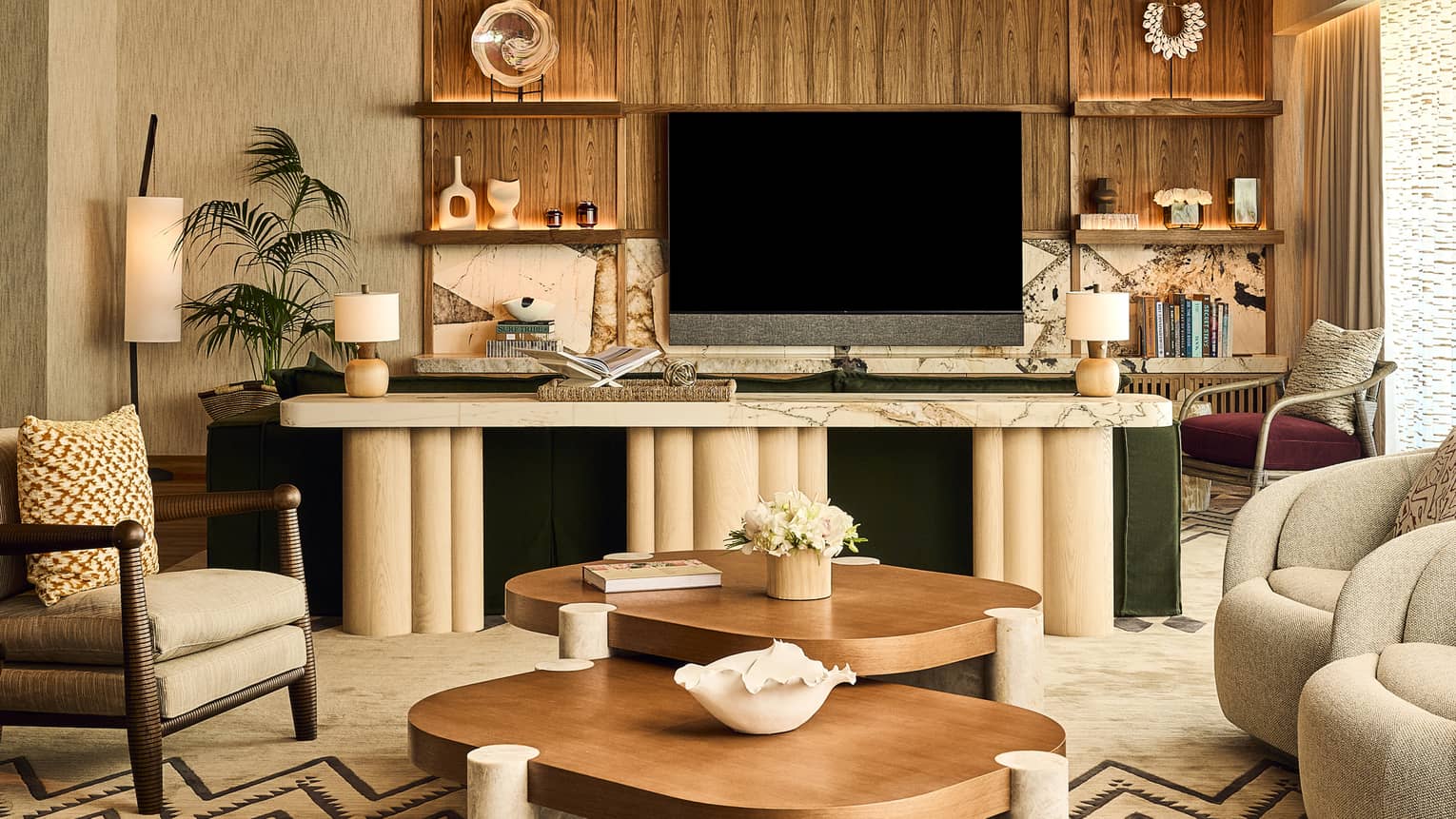 Stylish resort suite living room with arm chairs and two matching wood and stone coffee tables