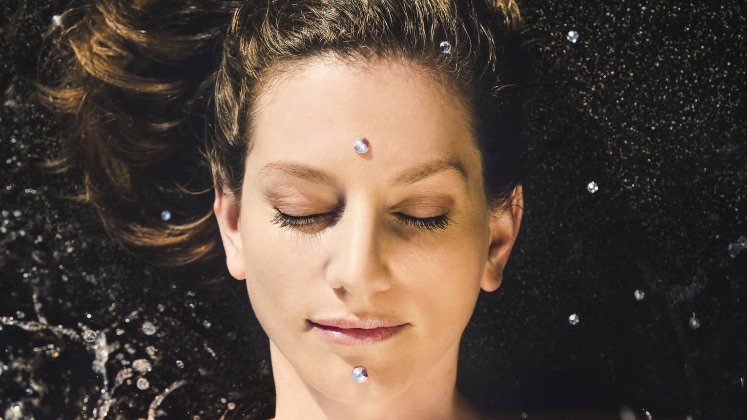 A woman enjoys a facial; two "black diamonds" are placed on forehead and chin