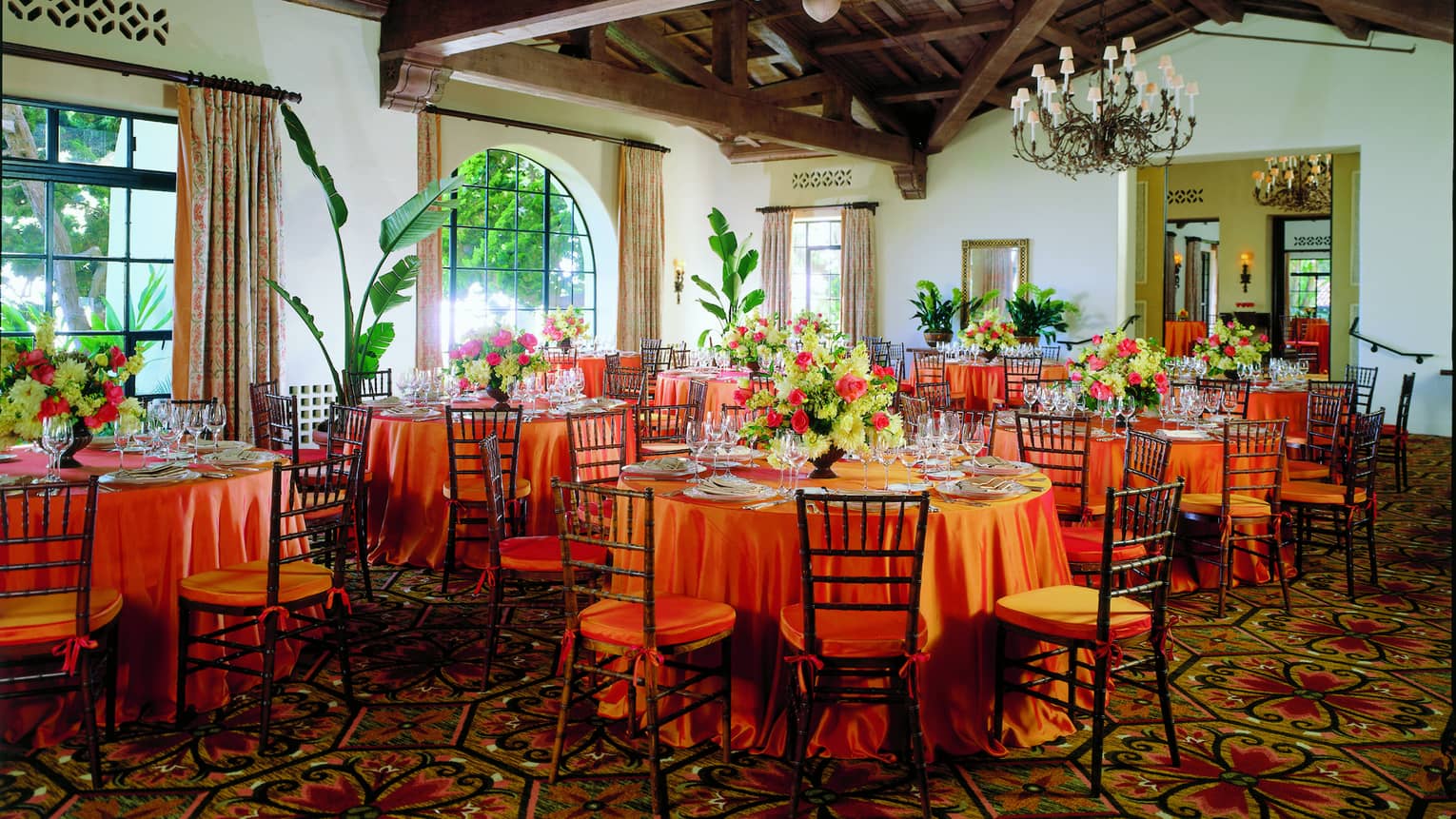 La Marina banquet tables under wood beam ceilings, sunny arched windows and tropical plants