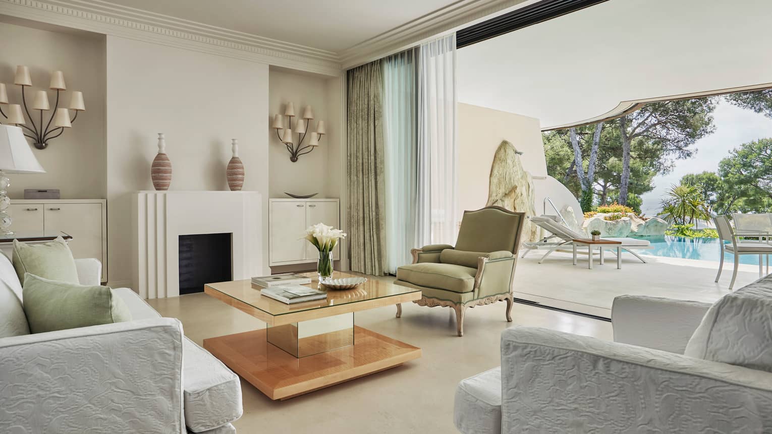 Pool Suite open-air living room with crisp white decor leading to sunny patio, pool