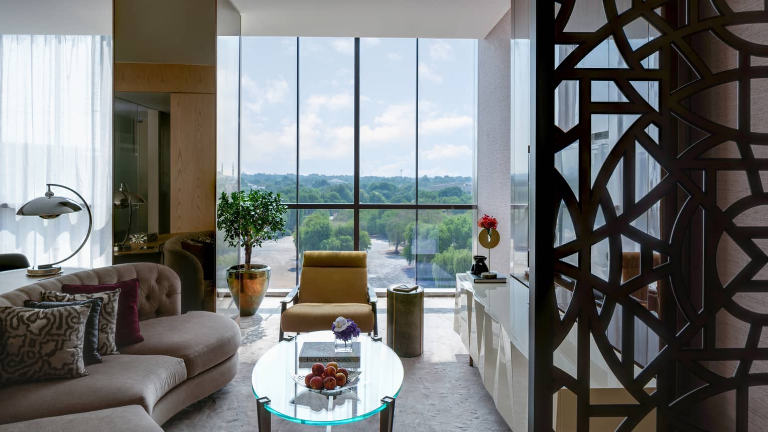 Living room with curved sofa, glass table and yellow arm chair