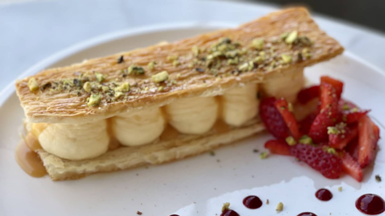 Sweet puff pastry filled with vanilla bean mousseline and garnished with strawberries and pistachio