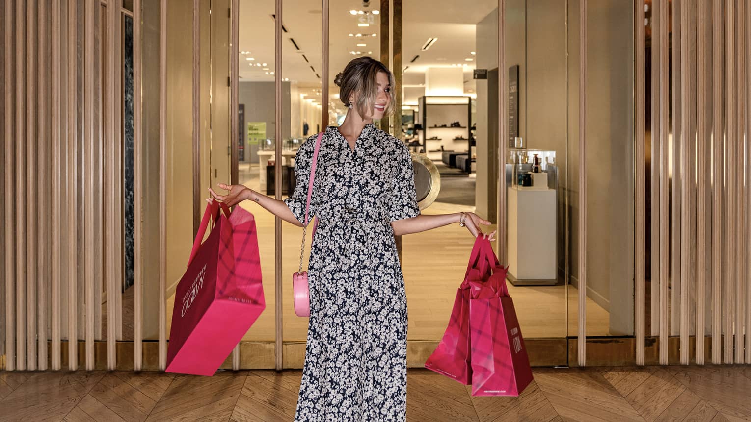 Person with arms full of pink shopping bags leaves Hotel Renfrew Ogilvy department store