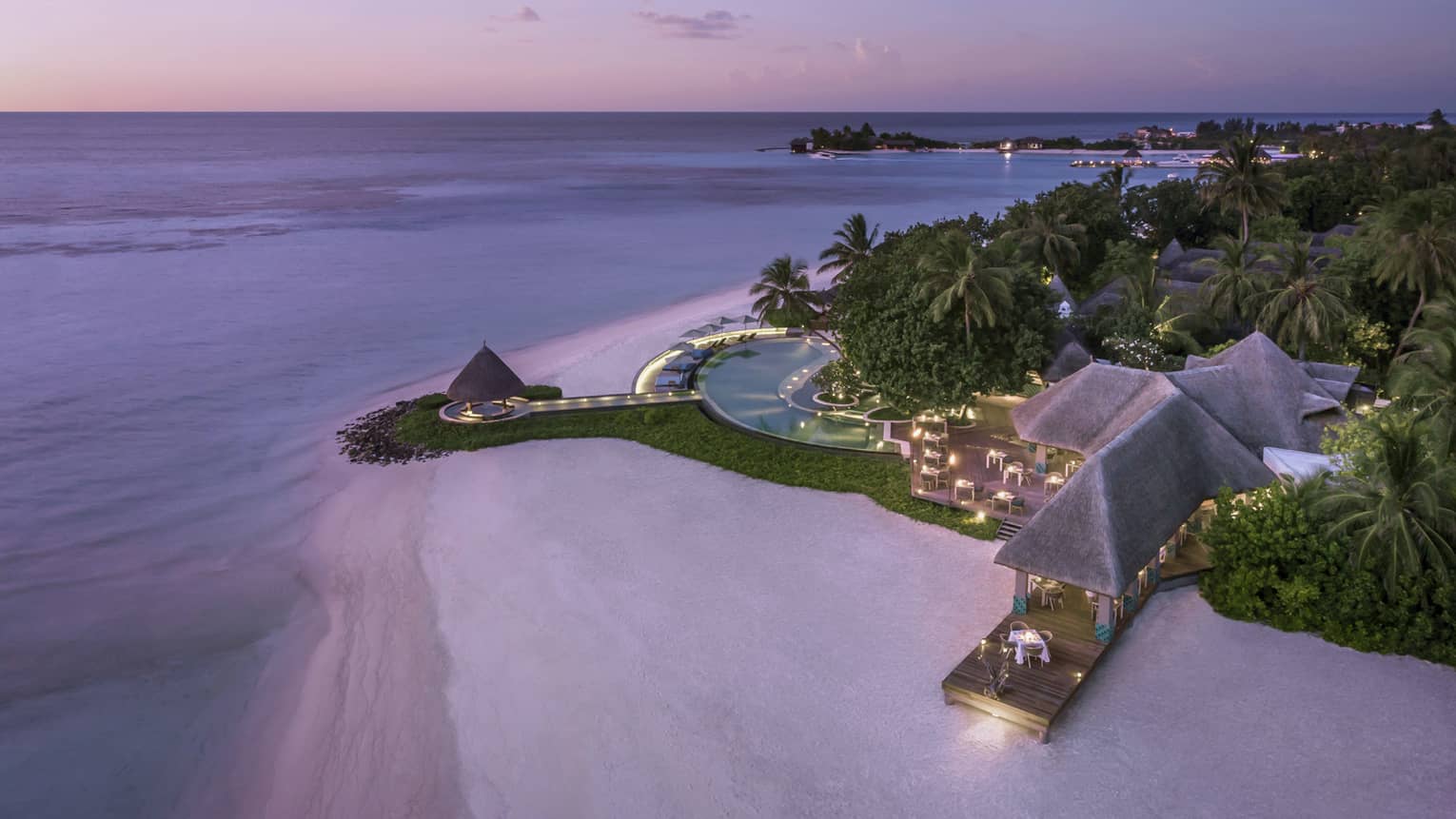 Aerial view of beach and Resort's illuminated deck with pool