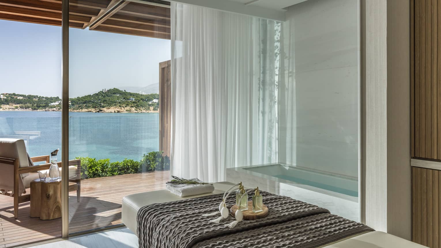 White spa table with dark blanket and water view from tall windows