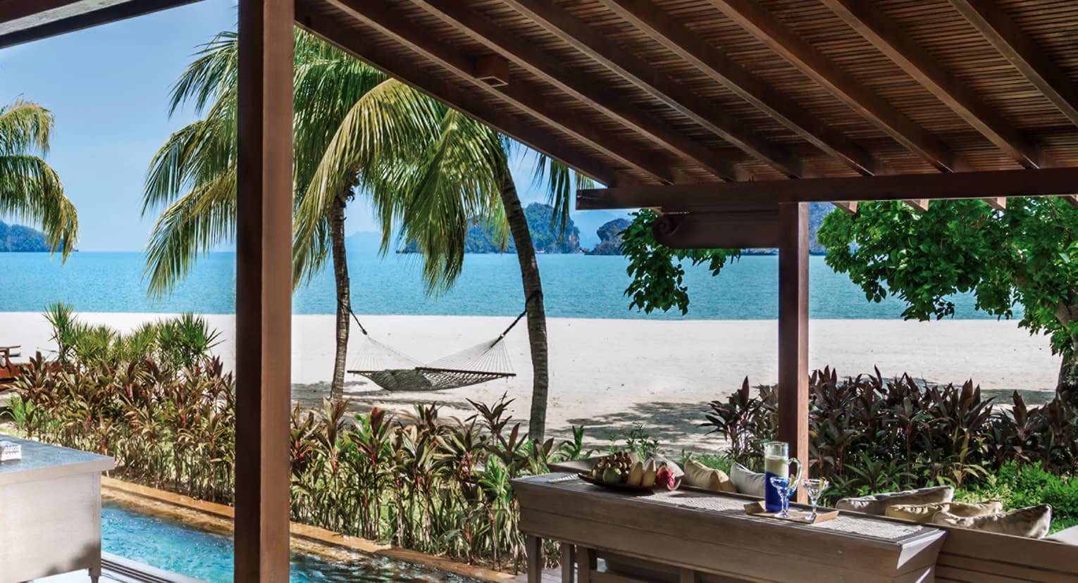 Villa awning over console table with fruit, drinks, plunge pool, by beach