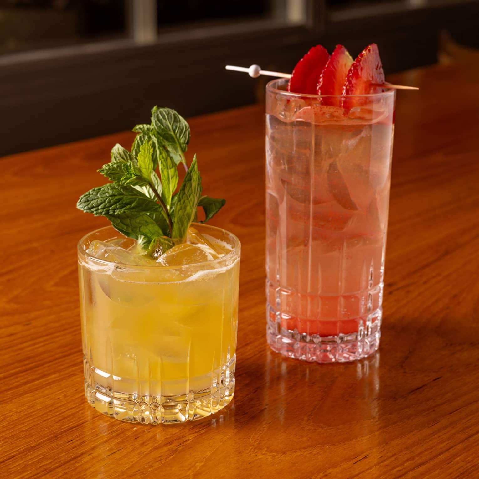 One yellow drink and one red drink placed beside each other on a dining table