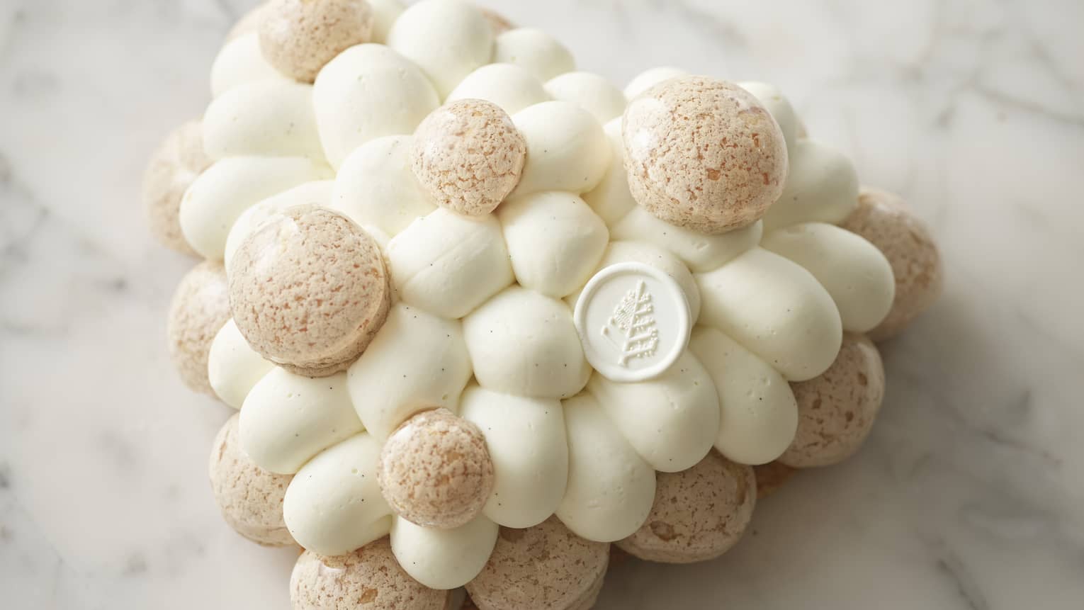 Heart-shaped white cake with piped mousse design and edible coin with Four Seasons logo