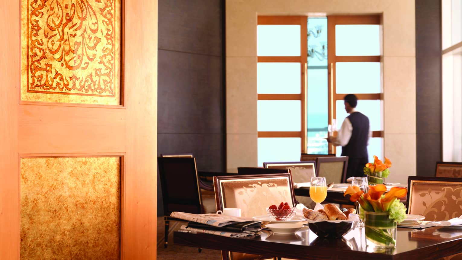 View past door to breakfast dining tables, waitstaff carrying tray
